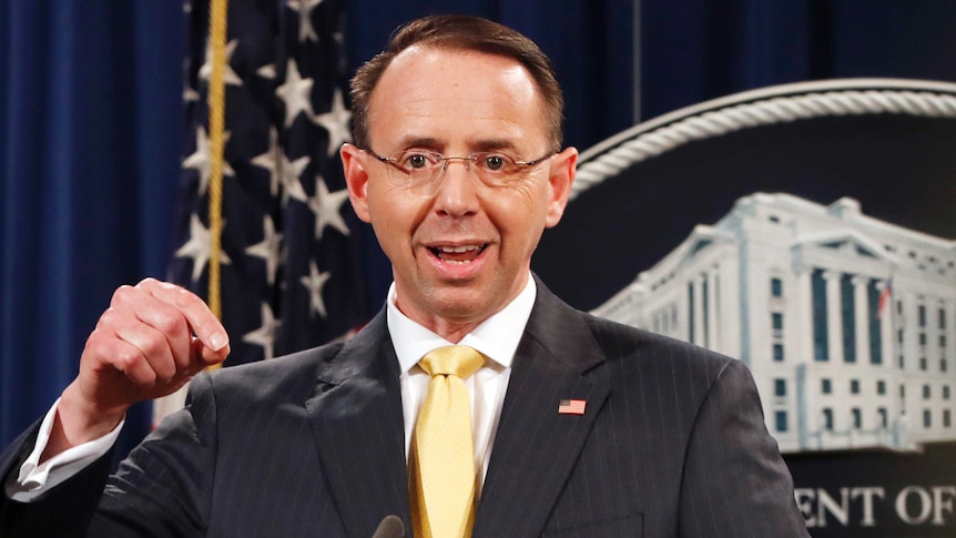 Rod Rosenstein - great name - makes a gesture with his hand as he speaks to media at a lectern