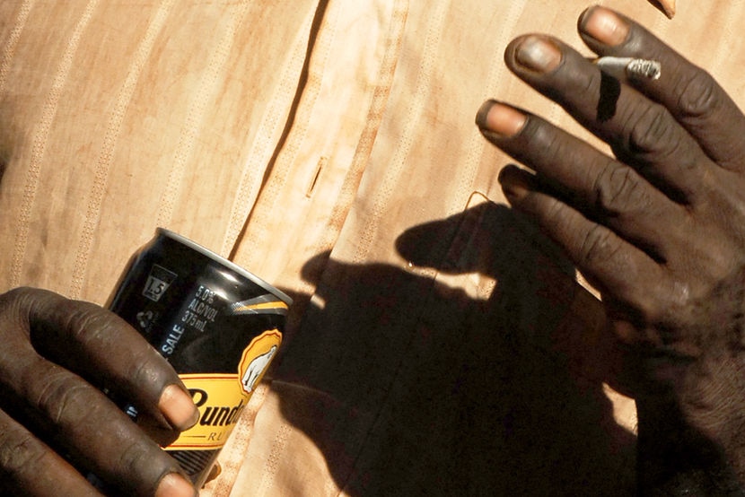 An Aboriginal man smokes a cigarette and drinks alcohol (File photo) (AAP: Dave Hunt)