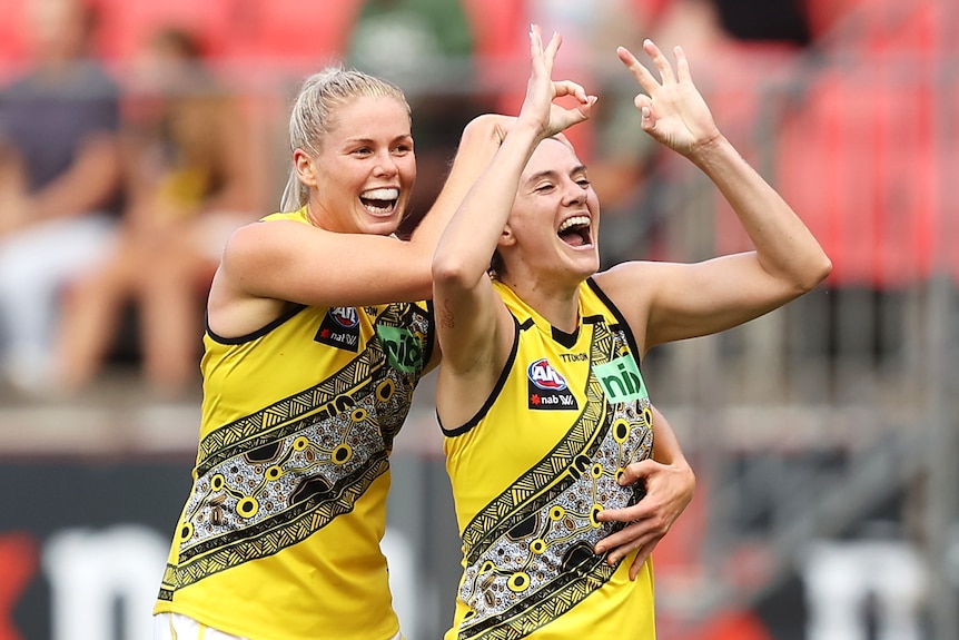 Two Richmond AFLW players celebrate a goal.