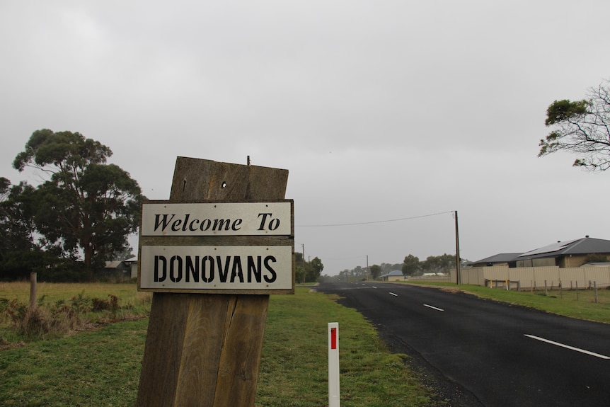 A silver sign reading 'welcome to Donovans' with a road stretching back behind