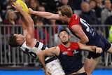 Tom Hawkins takes a contested mark between two Melbourne defenders