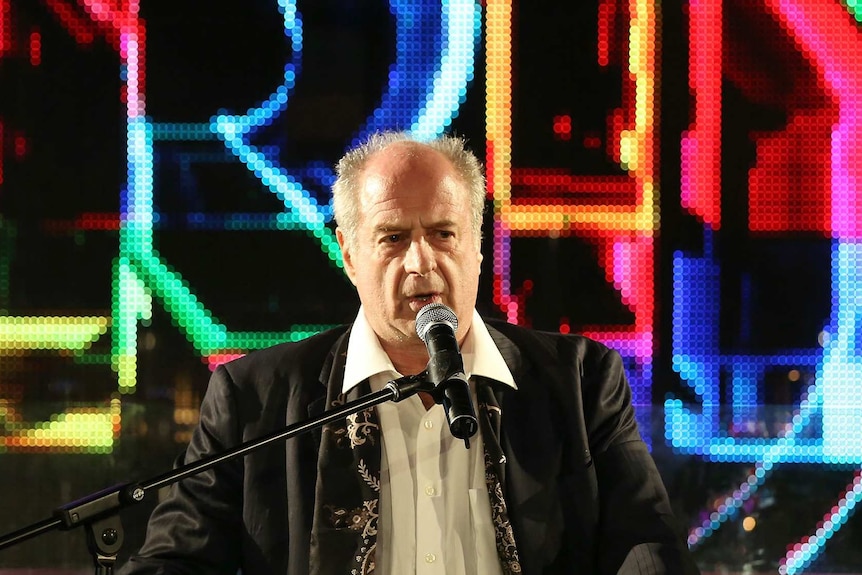 Michael Gudinski on a stage speaking into a microphone