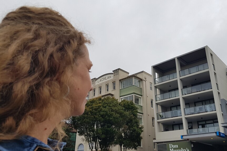 a person's side profile looking at apartments in the distance