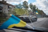Ukrainian service members ride on an armoured fighting vehicle in the town of Kupiansk,.
