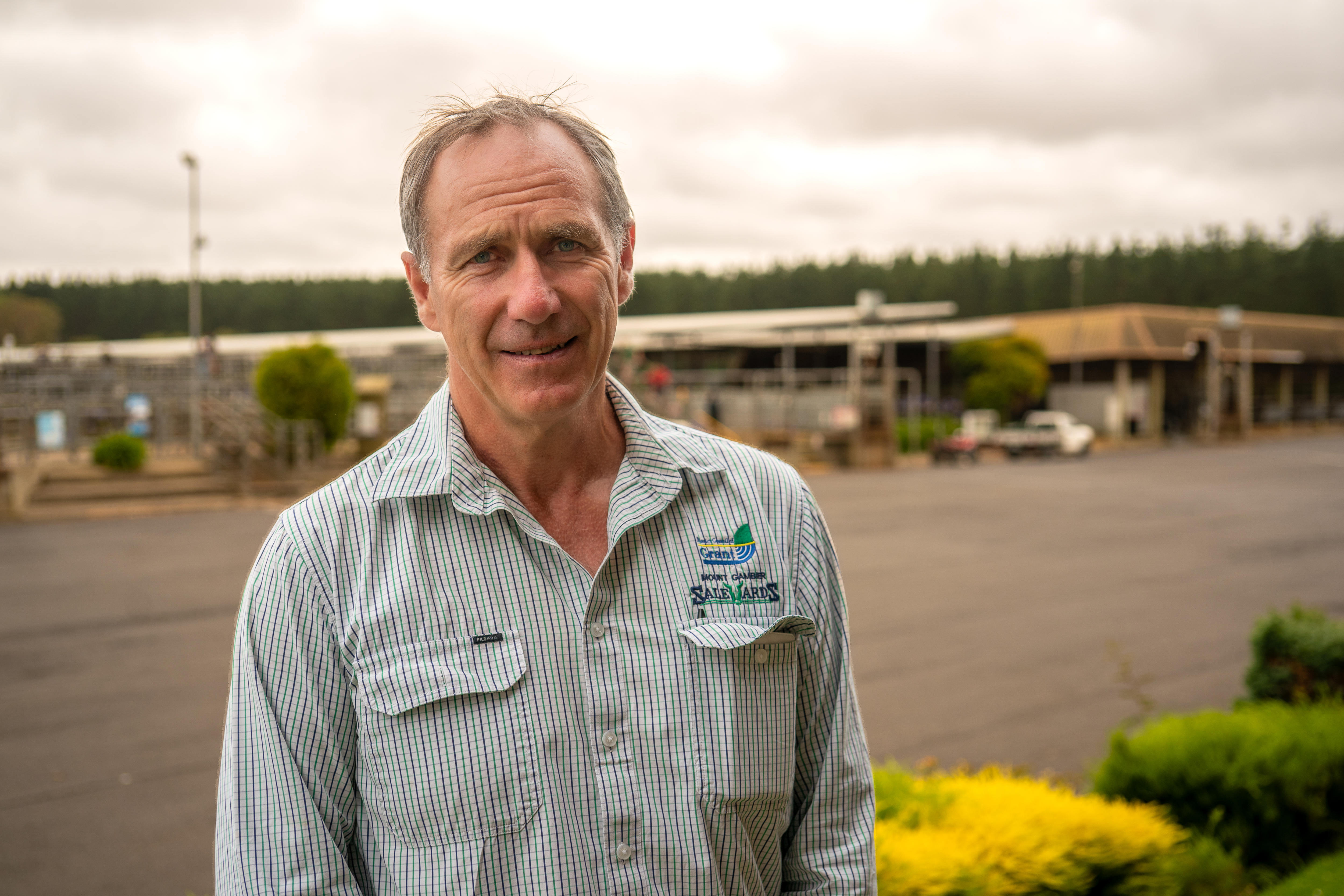 Un hombre mira a la cámara y al fondo una zona de ventas. 