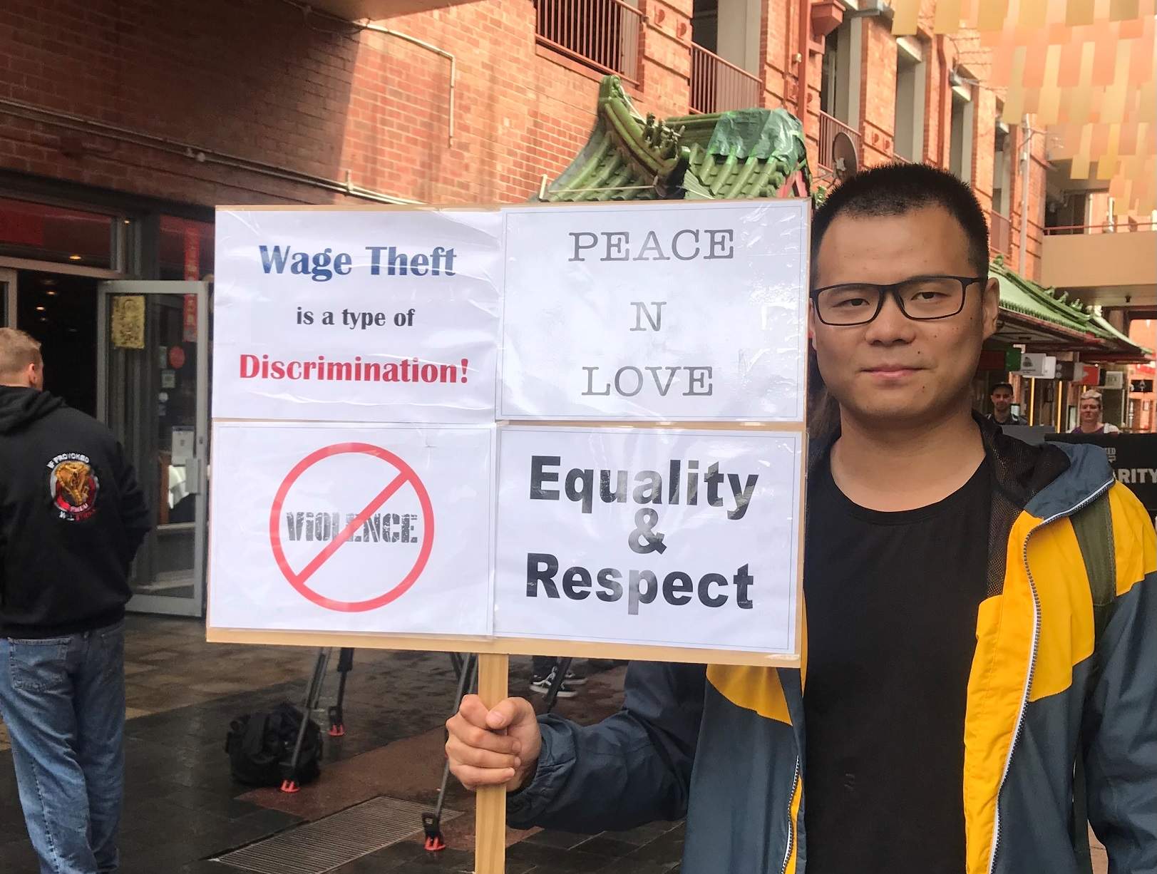 Jackie Chen from the SA Labour Info Hub holds a placard.