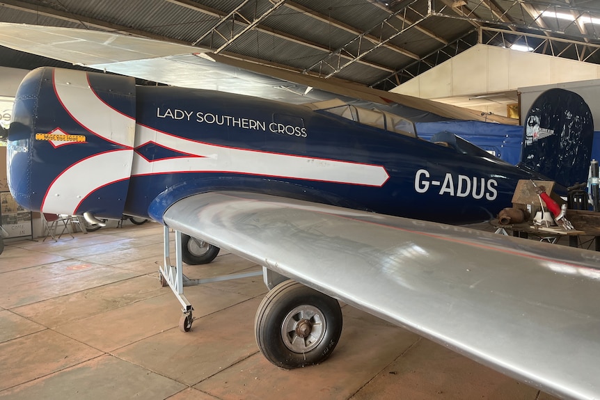 A replica of a vintage light aircraft, indoors at a museum, with the words Lady Southern Cross painted on the side