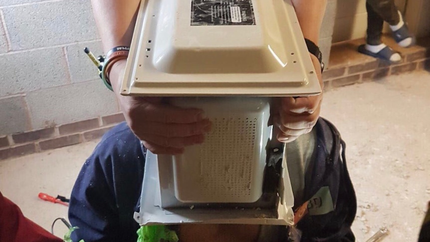 West Midlands fire authorities try to remove a man's head from inside a microwave
