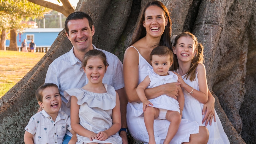 A man and woman sit under a tree with four children. For a story on telling children about a cancer diagnosis. 