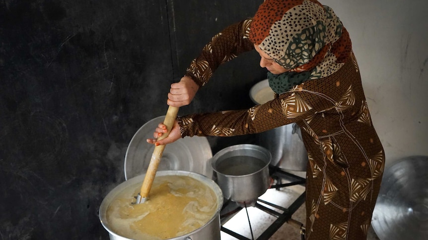 A woman stirring a huge pot of lentils
