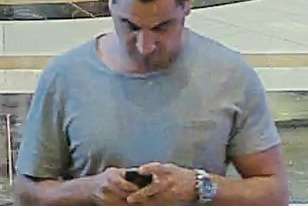 CCTV footage of a man walking and looking down at his phone.