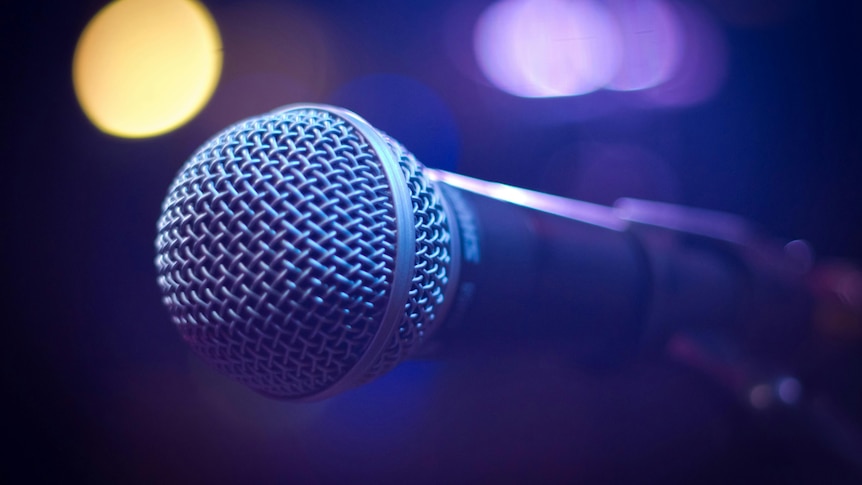 A round microphone with a blurred lights in the background.