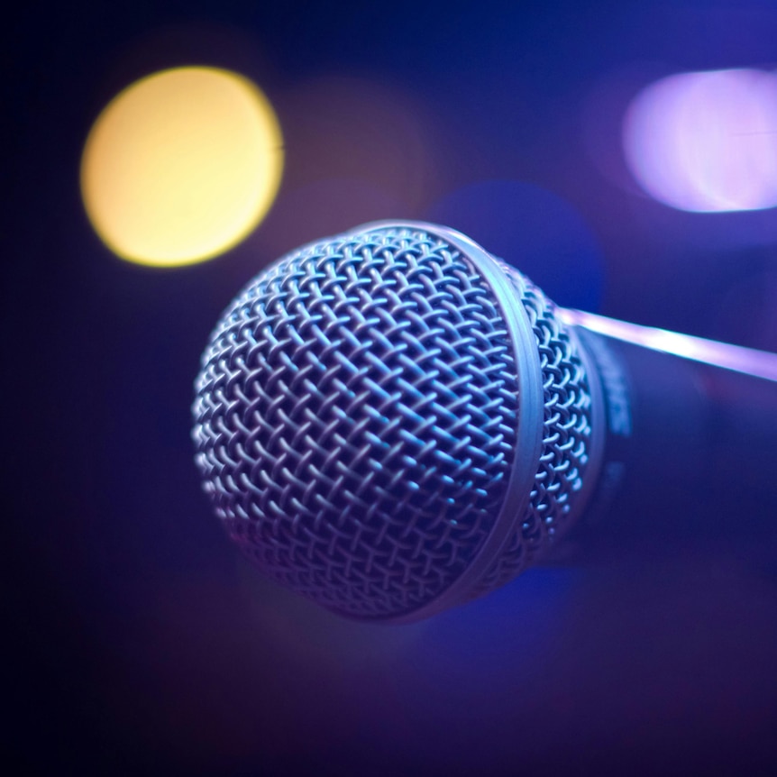 A round microphone with a blurred lights in the background.