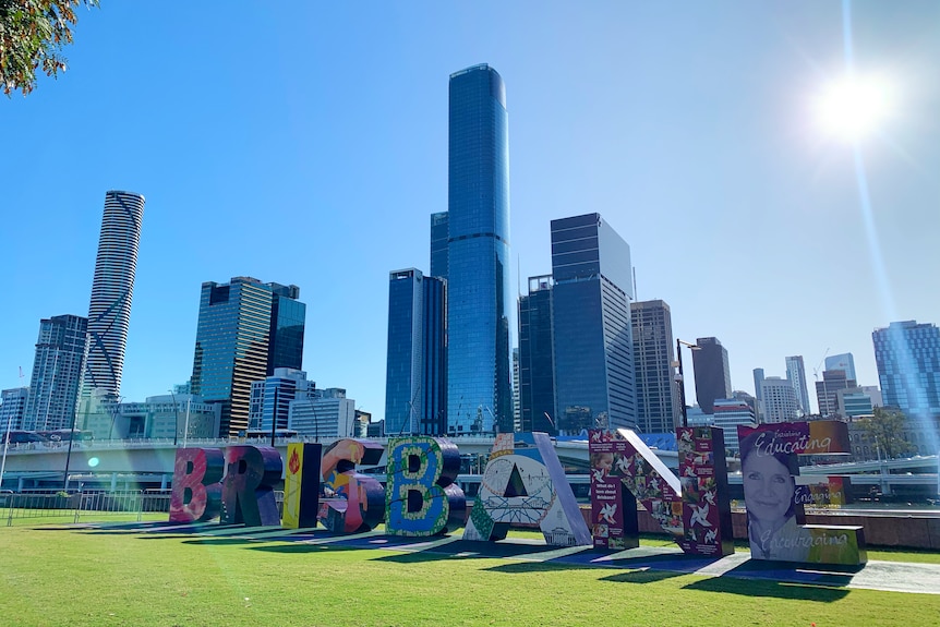 The city's skyline and sun overlook the Brisbane sign in Southport.