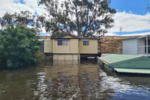 A yellow two story shack has water up to just below its second level. It is surrounded by other inundated properties. 