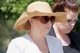 Julene Thorburn arrives at Beenleigh court wearing a straw hat and large sunglasses.