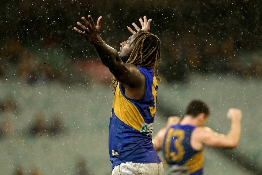 Nic Naitanui of the West Coast Eagles celebrates with his arms outstretched as the rain comes down.
