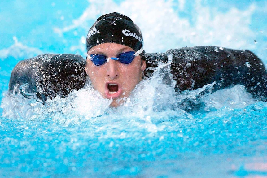 Ian Thorpe, in black swimming cap and long-sleeved swimsuit and blue goggles, comes up for air during a race.