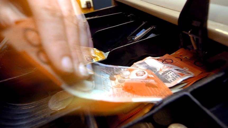 A shop assistant removes notes from a till