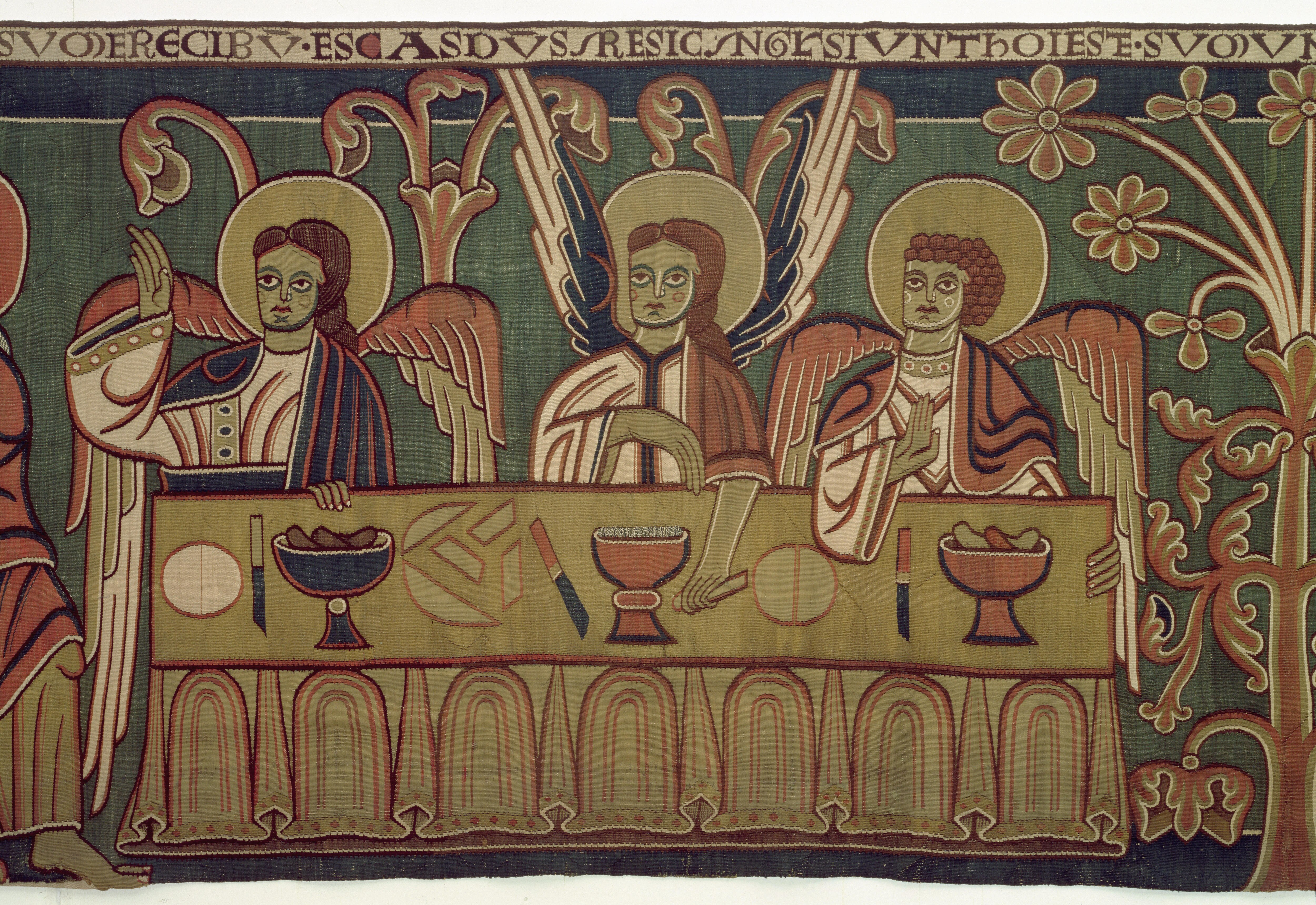A tapestry featuring three angel figures eating at a table