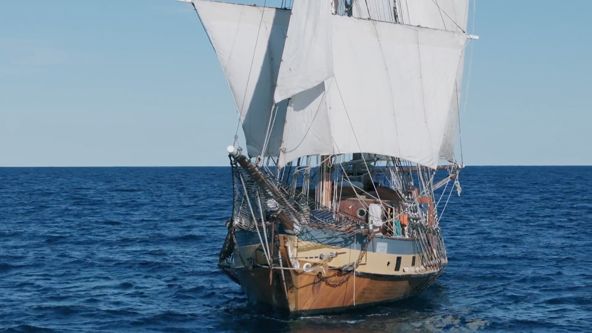 An old fashioned sailing boat on the seas with sails down.