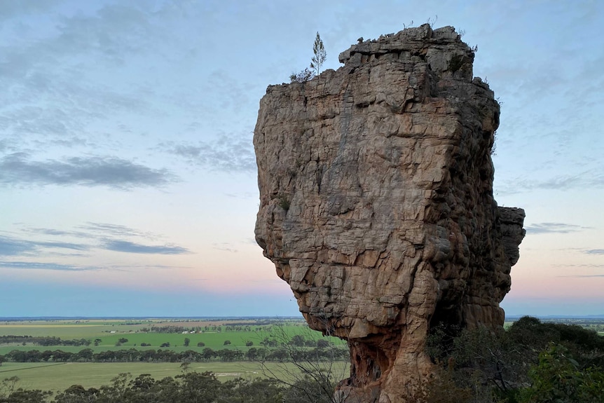 a large rock in the Wimmera overlooking vast plains of green and trees