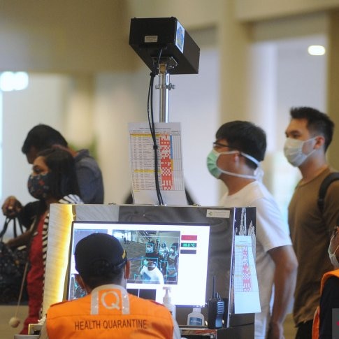 Officers checking body temperatures at the arrival terminal of Denpasar airport.