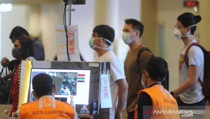 Officers checking body temperatures at the arrival terminal of Denpasar airport.