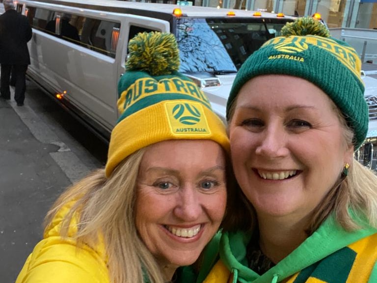 Two ladies wearing Matildas merch grin in a selfie with a white hummer. 