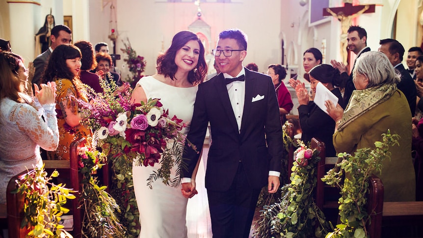 A bride and groom walking down the aisle at an unplugged wedding held in a Catholic church.