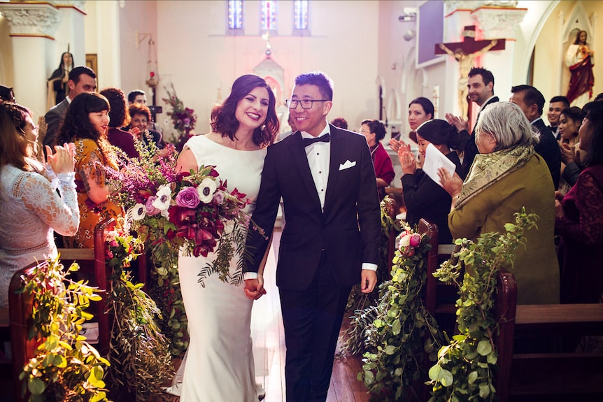 A bride and groom walking down the aisle at an unplugged wedding held in a Catholic church.