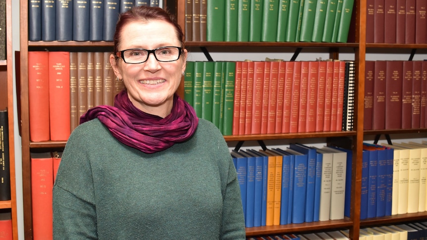 Julie Ross stands in front of a bookshelf.