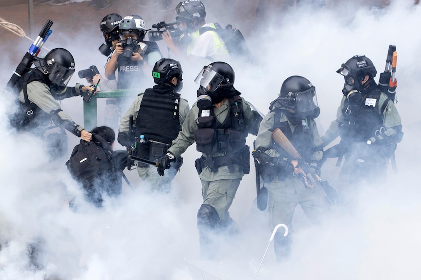 Police in riot gear move through a cloud of smoke as they detain a protester at the Hong Kong Polytechnic University.