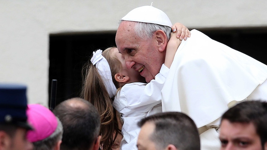 Pope Francis and a child hug during a general audience at the Vatican.
