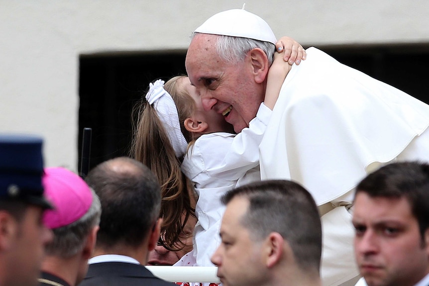 Pope Francis and a child hug during a general audience at the Vatican.