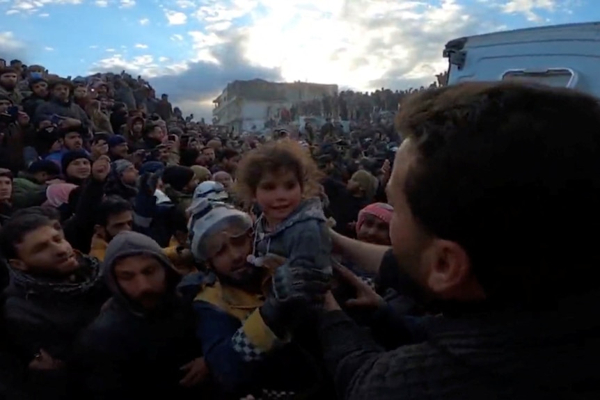 A family is rescued from rubble as a little girl is handed to rescue workers.