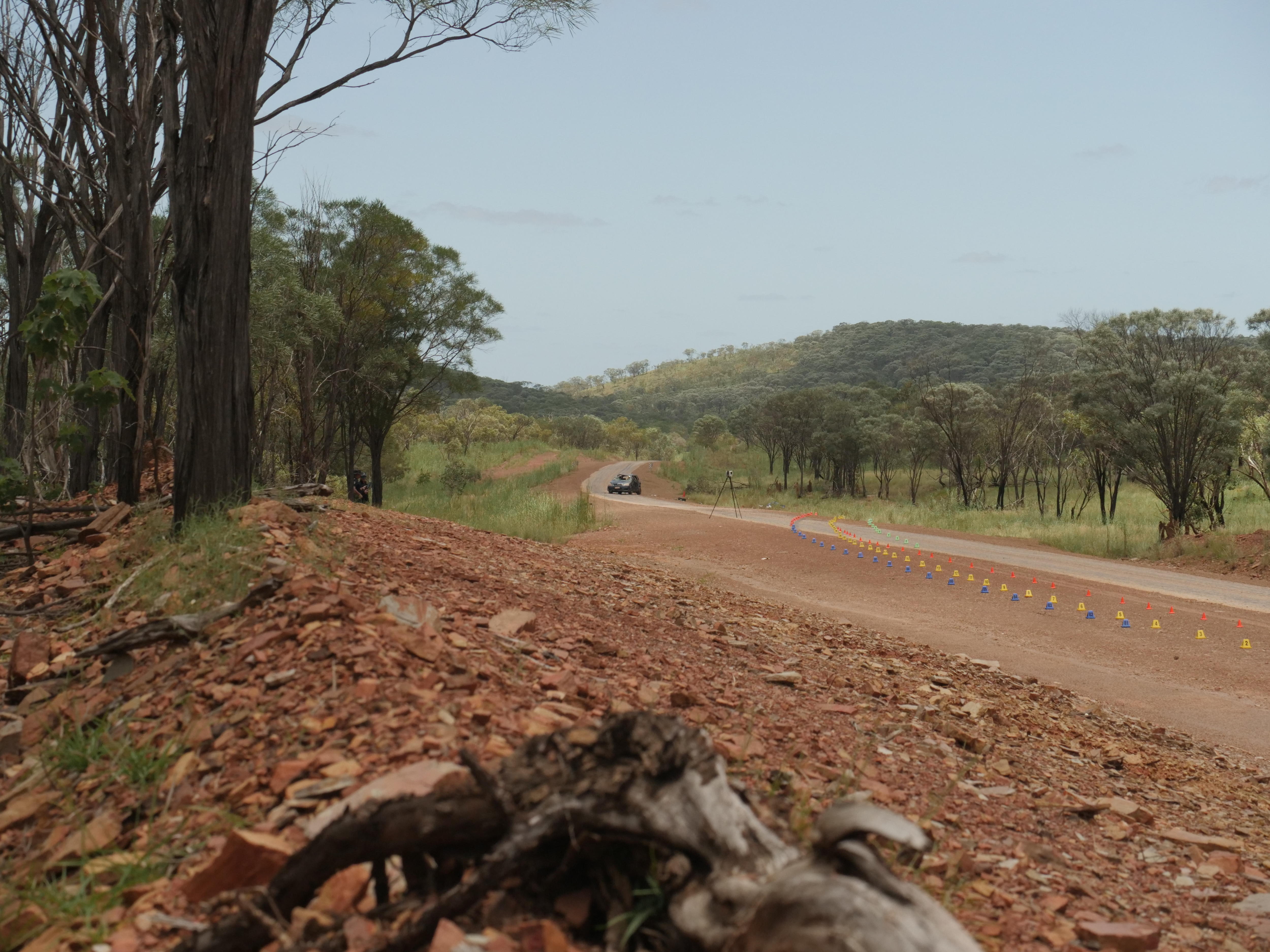 A remote highway with a crashed car in the middle with cones in front of it put down by police