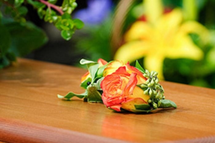 A wooden coffin with a rose on top.