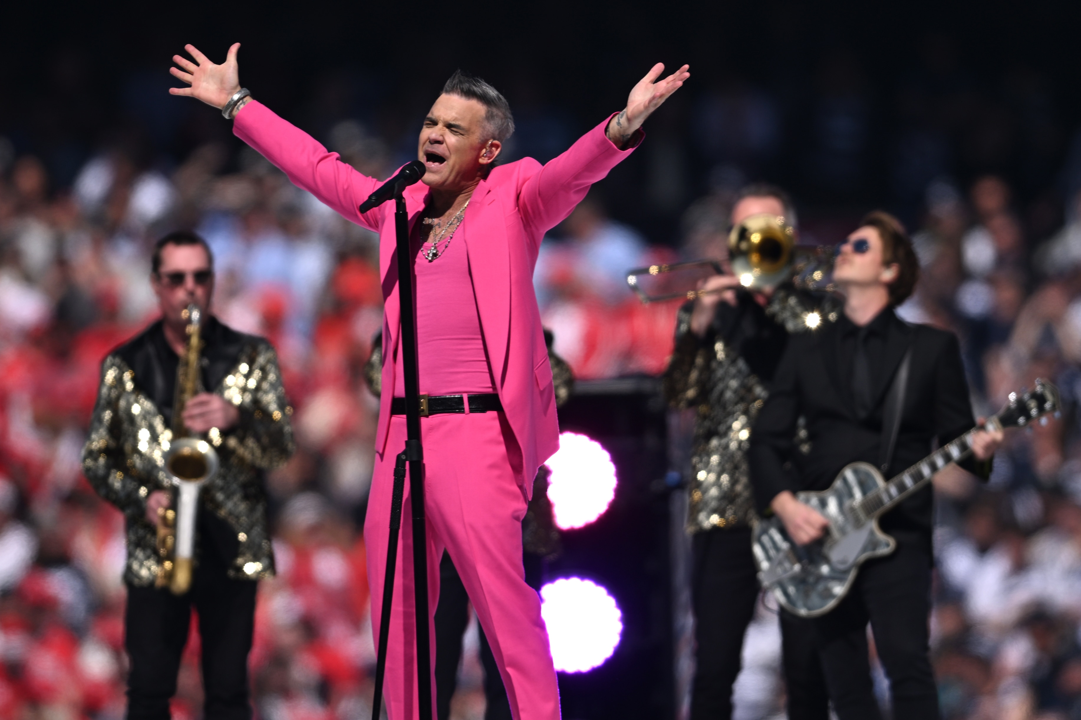 Singer Robbie Williams dressed in all one colour raises his arms in the air as he performs at the AFL Grand Final at the MCG.