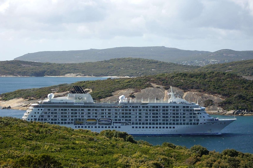 A cruise ship navigates between spectacular headlands.