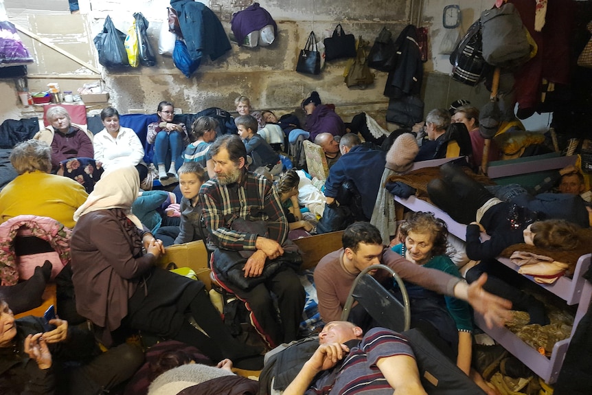 Residents of Yahidne are seen laying down next to each other inside the basement of a school.