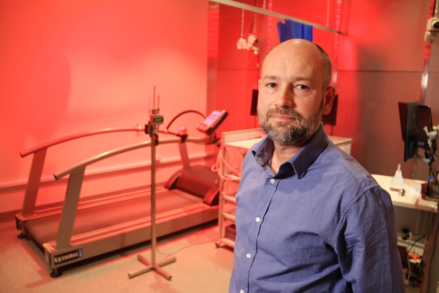 A white man with no hair on his head in a laboratory