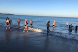 A wide shot of swimmers entering the water at Port Beach.