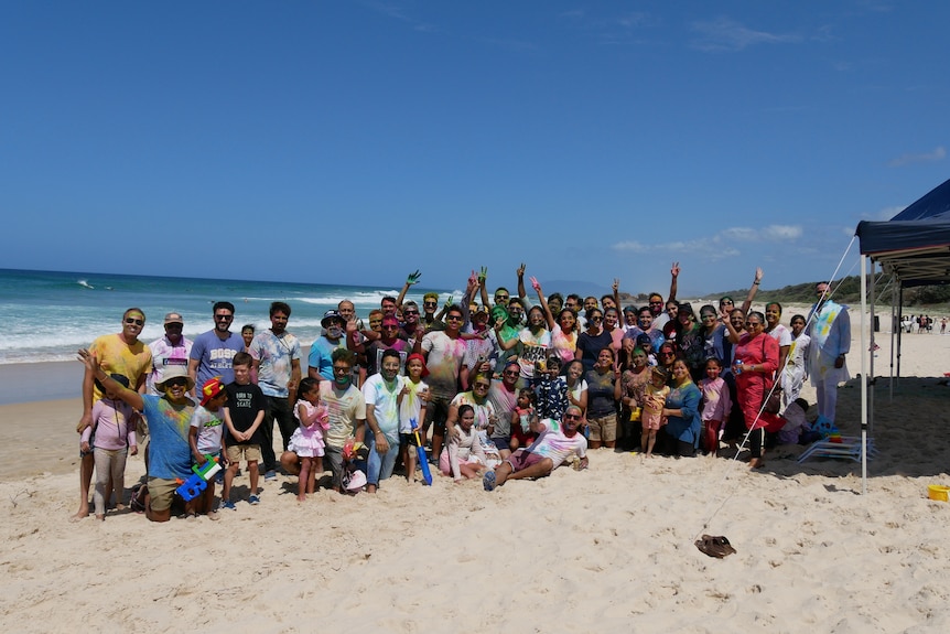 Large group of people hug and cheer while on the beach