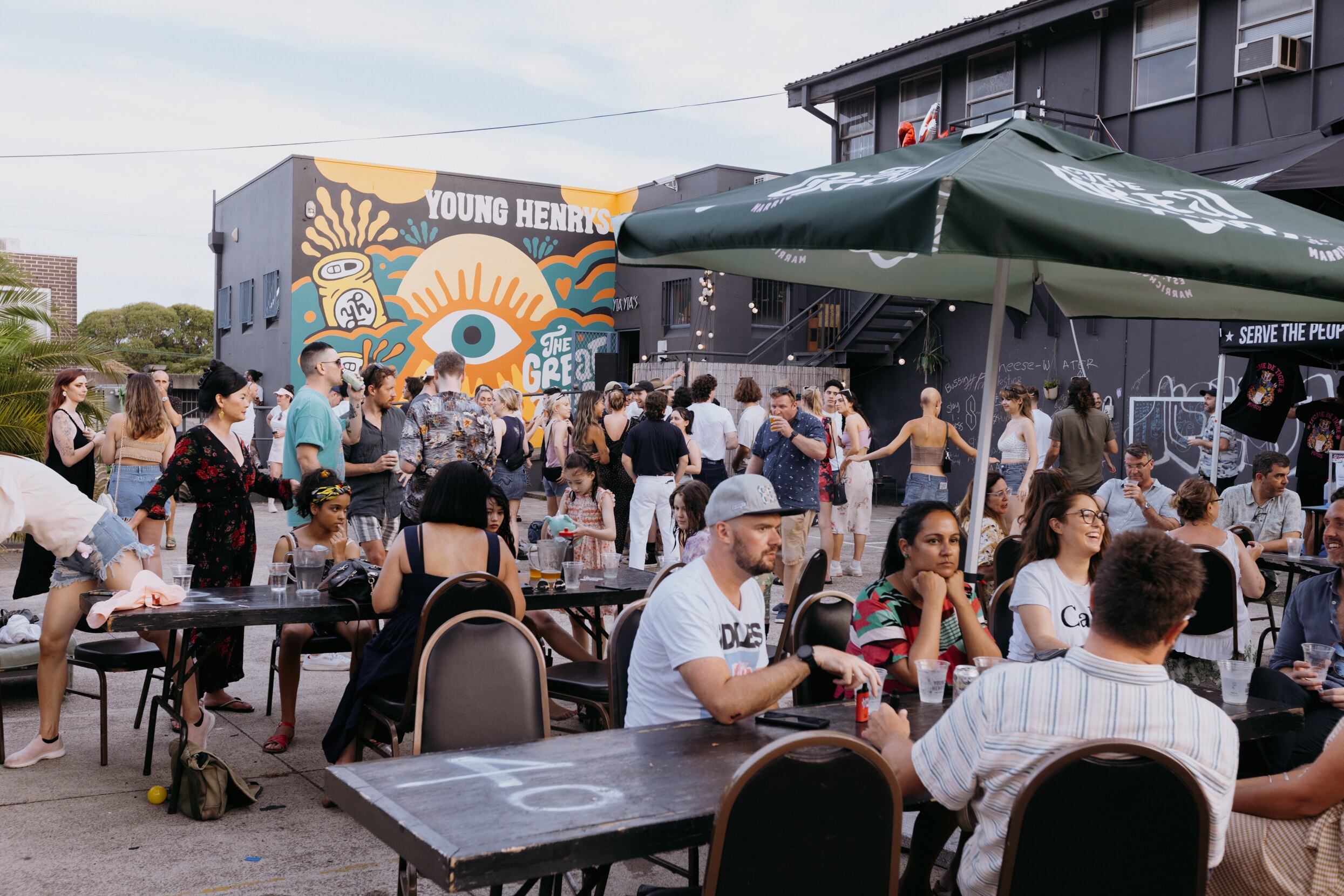 A crowded beer garden with a muralled wall in the background.
