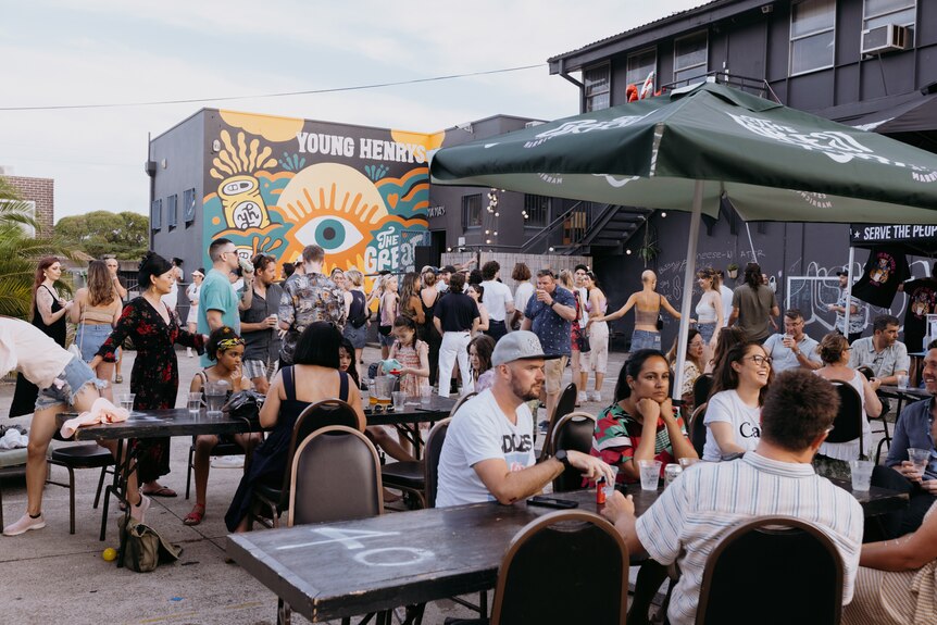 A crowded beer garden with a muralled wall in the background.