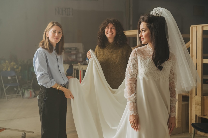 Director Sofia Coppola, Costume Designer Stacey Battat hold a wedding dress worn by actor Cailee Spaeny who is looking back