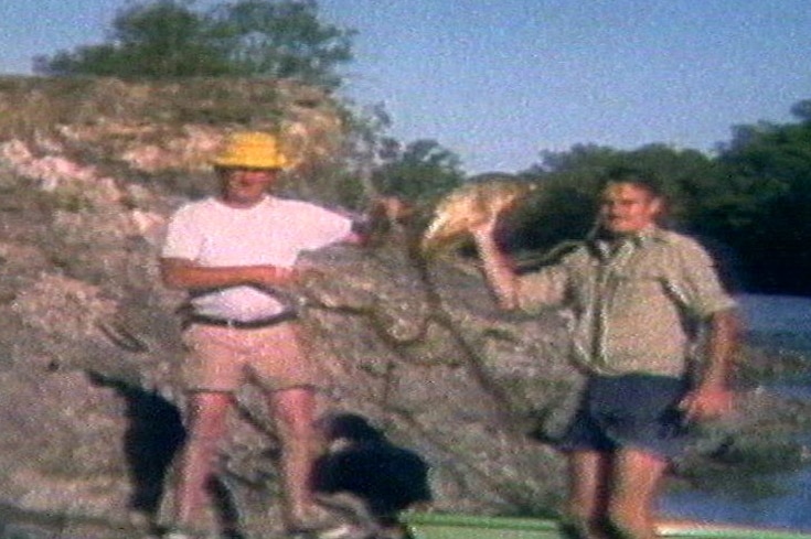 Colin Winchester stands with a friend holding a fish.