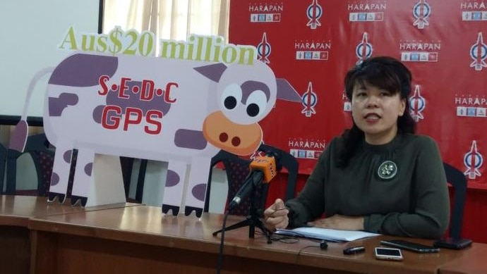a woman at a press conference with a prop of a cow next to her.