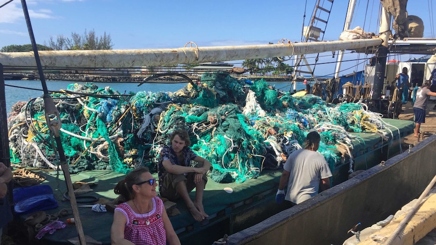 A large pile of knotted and rotten nets are piled on a boat